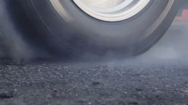 Sürüklenen yarış arabası yarışa hazırlanırken lastiklerini yakıyor.