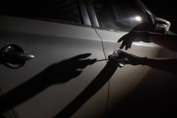 Ladrão de carros usando uma ferramenta para invadir um carro — Fotografia de Stock