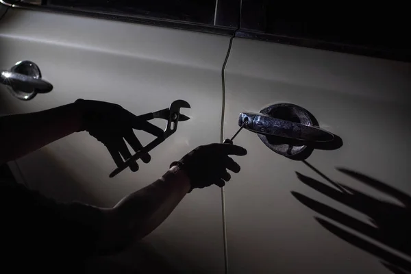 Car thief using a tool to break into a car — Stock Photo, Image