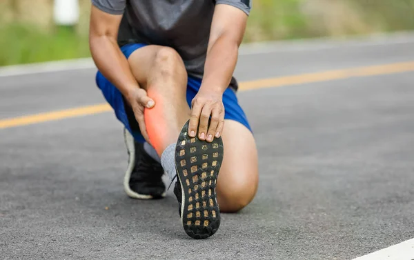 Male middle aged having a cramp while jogging. Stop and massage — Stock Photo, Image