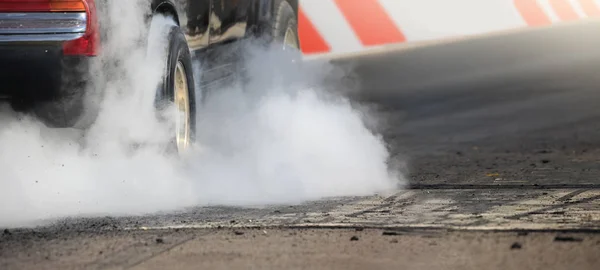 Drag carro de corrida queima borracha fora de seus pneus em preparação para a corrida — Fotografia de Stock