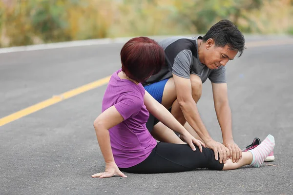 Kvinna medelålders med en kramp medan jogging, massage kalv — Stockfoto