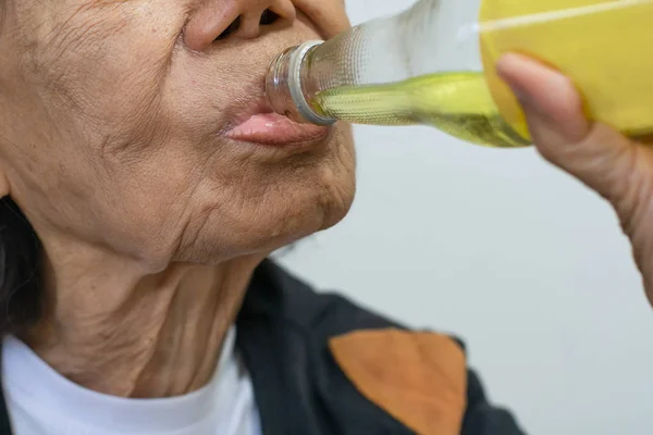 Пожилая азиатка пьет минеральный лимон — стоковое фото