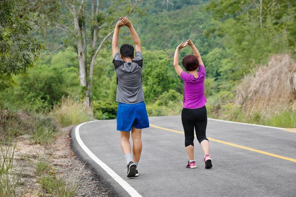 Asiático casal de meia idade alongamento músculos antes de correr em pa — Fotografia de Stock