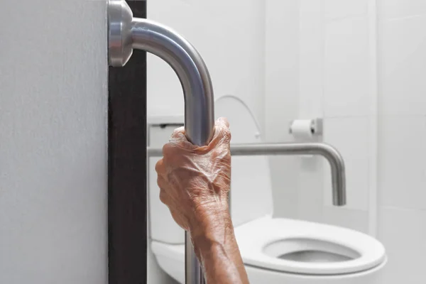 Bejaarde vrouw houden over de leuning in badkamer — Stockfoto