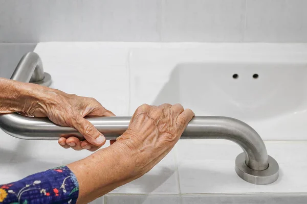 Bejaarde vrouw houden over de leuning in badkamer — Stockfoto