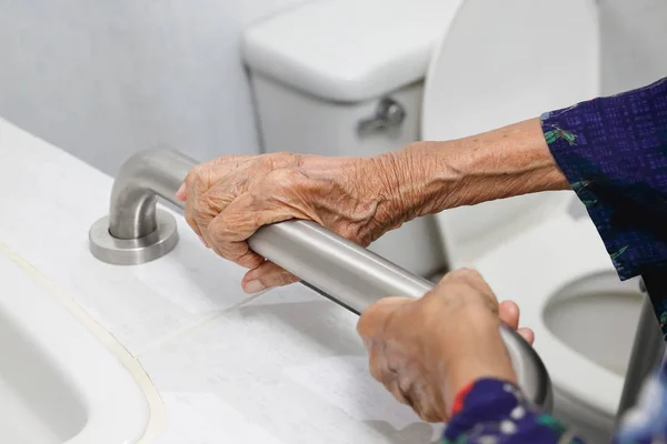 Bejaarde vrouw houden over de leuning in badkamer — Stockfoto