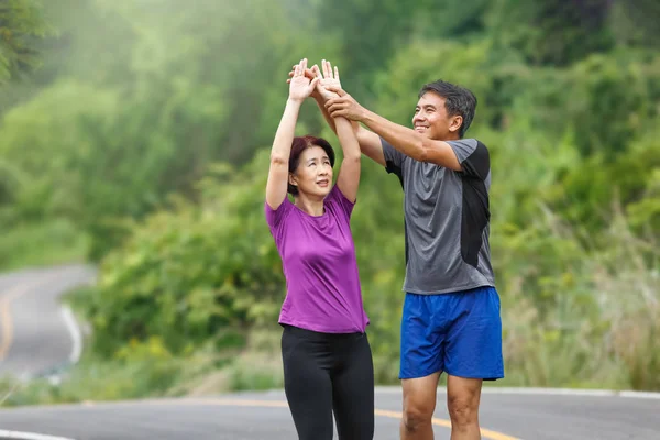 Asiatiska medelålders par stretching muskler innan jogging i PA — Stockfoto