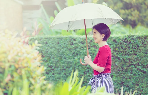 Średnim wieku Asian kobieta trzyma parasol w silnym słońcu — Zdjęcie stockowe