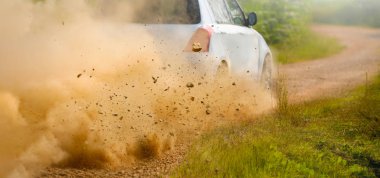 Ralli arabasından çıkan çakıl taşları toprak yolda sürükleniyor.