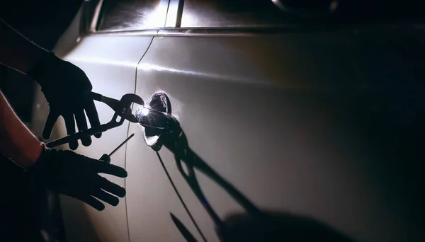 Car thief using a tool to break into a car — Stock Photo, Image