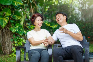 Orta yaşlı çift rahatlar arka bahçede bankta otururlar..