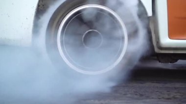 Sürüklenen yarış arabası yarışa hazırlanırken lastiklerini yakıyor.