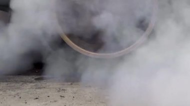 Sürüklenen yarış arabası yarışa hazırlanırken lastiklerini yakıyor.