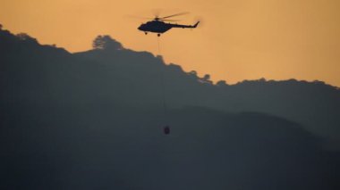 Yangın söndürme helikopteri orman yangınına su bırakıyor.