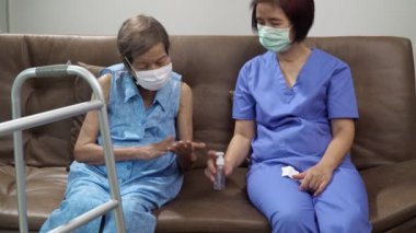 Yaşlı bir kadın bakıcıdan tutun da Coronavirus covid-19 'a kadar el dezenfektanı sürüyor.