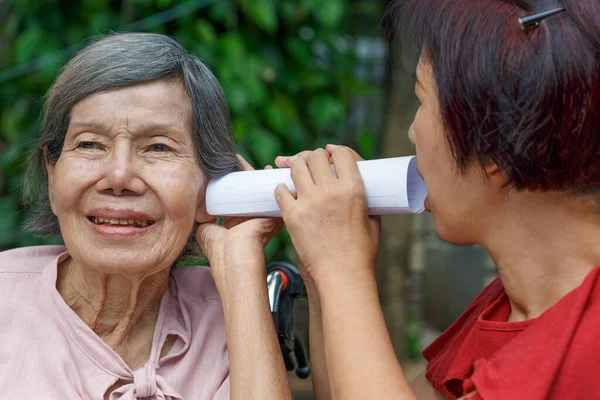 使用纸管与听力受损老年妇女交谈的女儿 — 图库照片