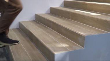 Yetişkin bir adam merdivenlerden kayıp düşüyor.