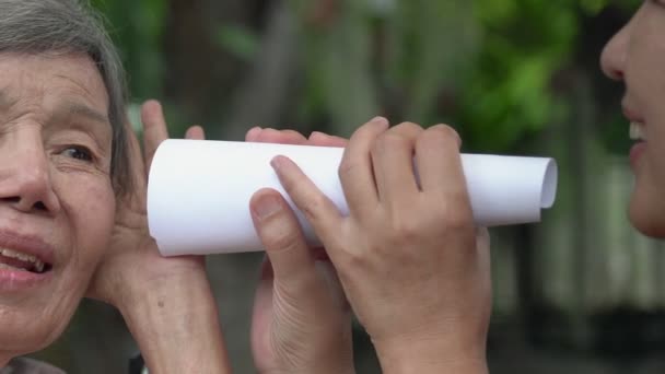 使用纸管与听力受损老年妇女交谈的女儿 — 图库视频影像