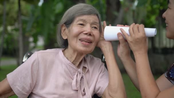 Κόρη Μιλάει Ηλικιωμένη Γυναίκα Προβλήματα Ακοής Χρησιμοποιώντας Χάρτινο Σωλήνα — Αρχείο Βίντεο