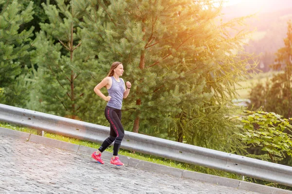 Giovane donna sportiva che corre giù sulla strada acciottolata — Foto Stock