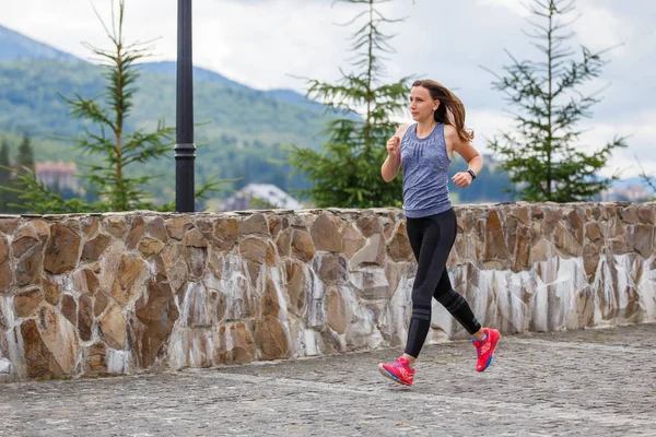 Young woman running in mountain european town in the morning — Stock Photo, Image