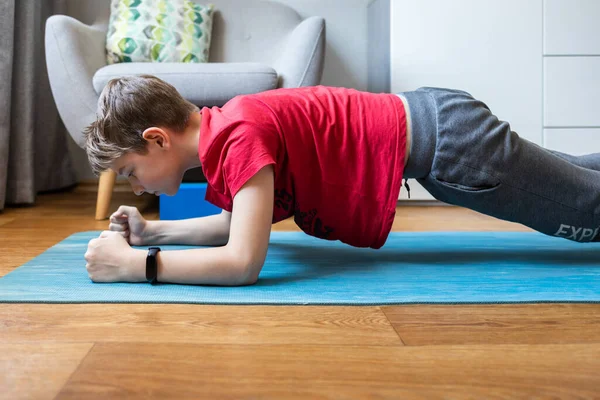 Boy holding forearm plank pose doing yoga at home — Stock Photo, Image