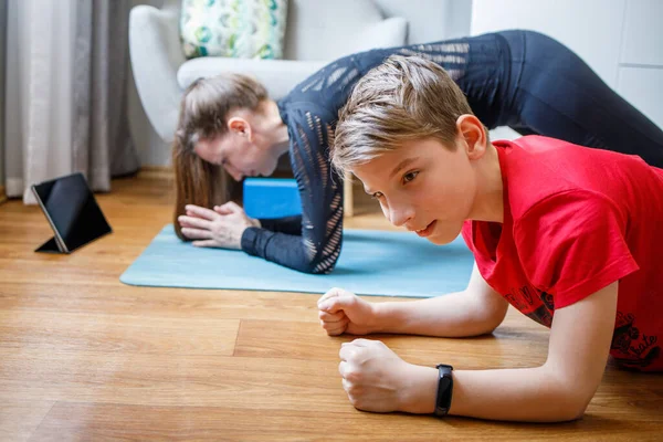 Niño pequeño con su madre practicando yoga en casa —  Fotos de Stock