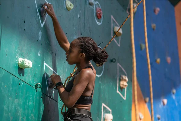 Junge schwarze Frau klettert an Kletterwand — Stockfoto