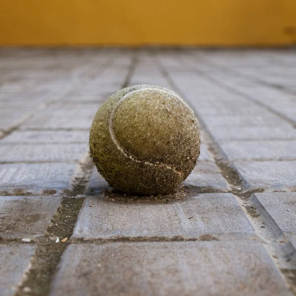 Old and dirty tennis ball in floor perspective