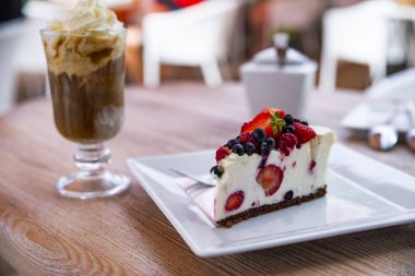 Cheesecake taze meyve ve arka planda buzlu kahve