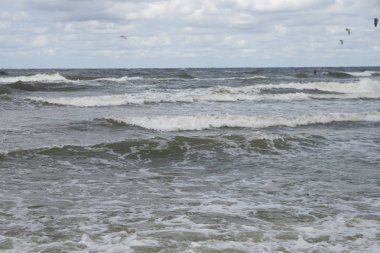Denizde dalgalar ve arka planda uçurtmalar