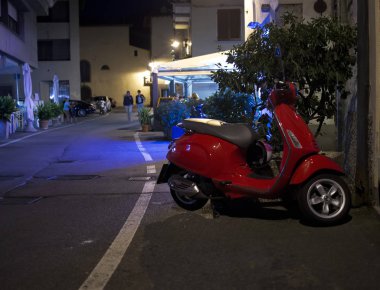 Arka planda restoranı olan İtalyan bir sokakta motosiklet, doğal ışık.