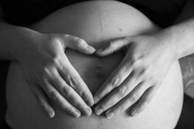 Hamile bir kadının karnı üzerinde bir kalp şeklinde el