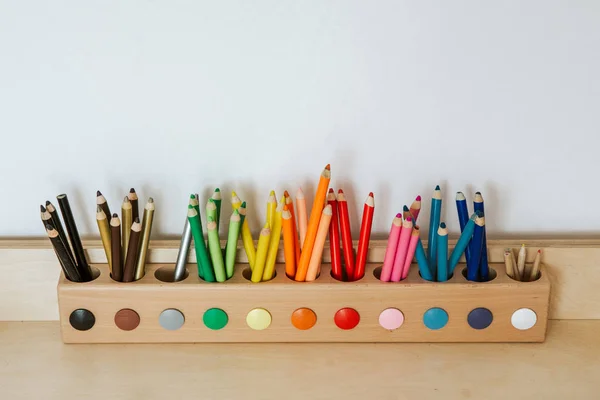 Lápis coloridos em um recipiente em uma mesa de madeira — Fotografia de Stock