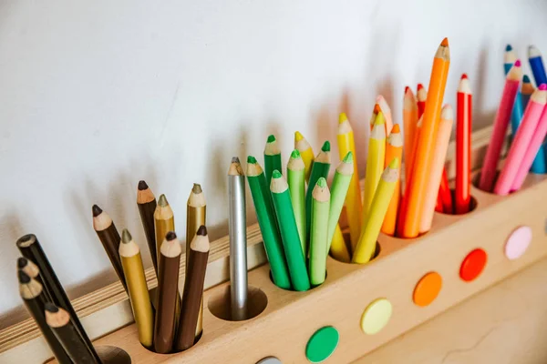 Цветные карандаши в контейнере на деревянном столе, закрываются на зелени — стоковое фото