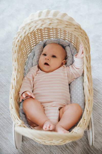 newborn in a toy wicker trolley, top view