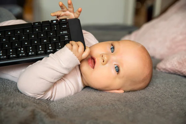 small child, first steps on the internet, a newborn baby is holding a keyboard from the computer