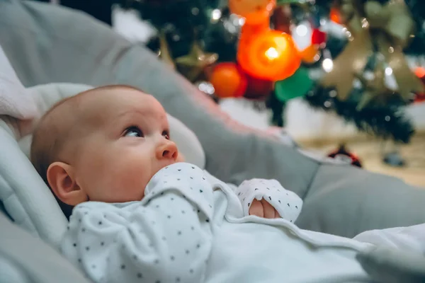 Zblízka na novorozence vyhlížel ven, vánoční stromek na pozadí — Stock fotografie