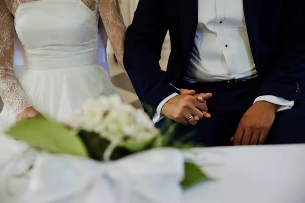 La joven pareja se coge de la mano durante la boda — Foto de Stock