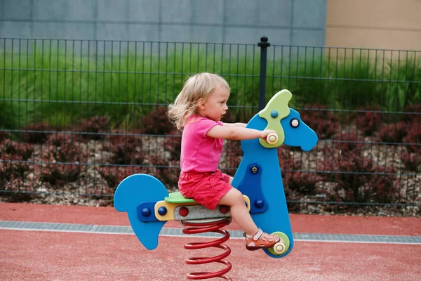 Mädchen Auf Dem Kinderspielplatz Reiten lizenzfreie Stockfotos