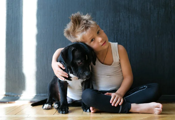 Little blond boy playing with a puppy at home — Stock Photo, Image