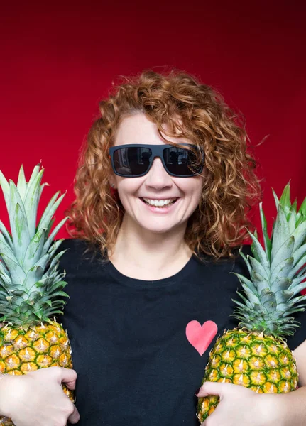 Red-haired beaut in a black t-shirt with a print of heart hold a — Stock Photo, Image