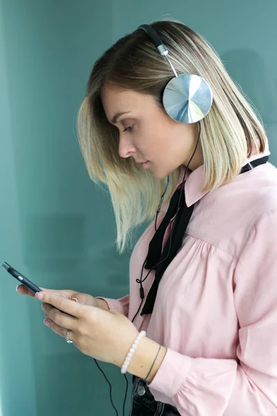 Linda loira em fones de ouvido de prata escuta música. Elegante — Fotografia de Stock