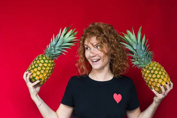 Red-haired beaut in a black t-shirt with a print of heart hold a Royalty Free Stock Photos