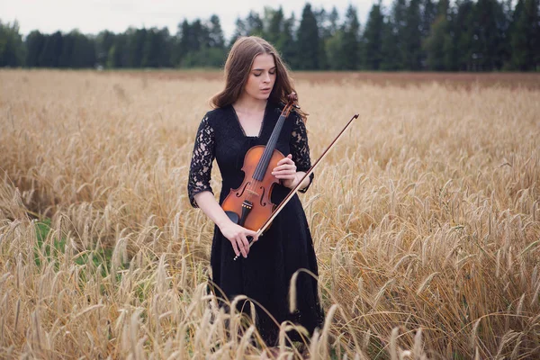 서있는 아름다운 여성이 바이올린을 누릅니다 — 스톡 사진