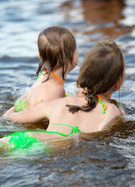İki kız kardeş nehirde yüzerken eğlenceli oynarlar. Harika bir ruh hali. Duyguları