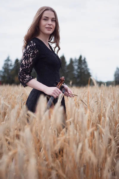 smiling contented young woman violinist on a beautiful field