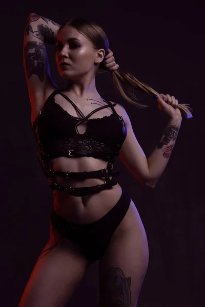 Eine sexy junge Frau in schwarzer Unterwäsche und Ledergürtel richtet ihr üppiges Haar mit dem Rücken zur Kamera — Stockfoto