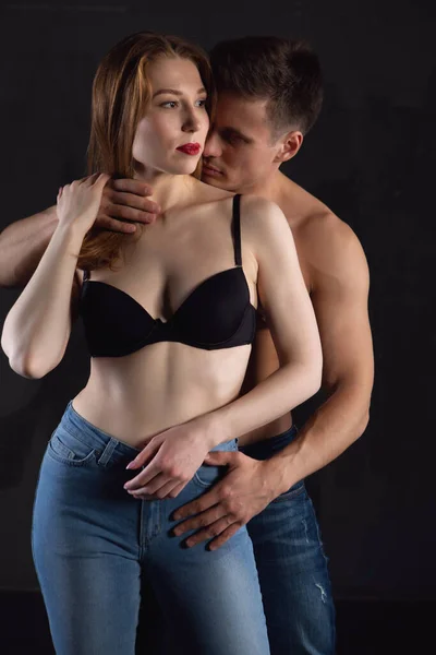 Una hermosa pareja joven enamorada se abraza tiernamente sobre un fondo negro aislado — Foto de Stock